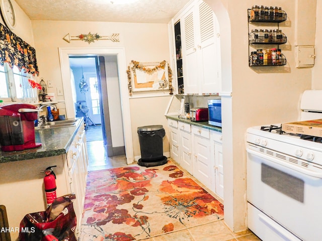 kitchen with sink, a textured ceiling, white cabinets, and white range with gas stovetop