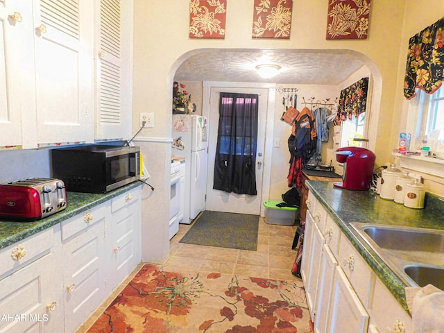 kitchen with white cabinetry, sink, light tile patterned floors, and white appliances