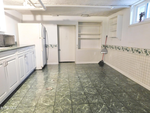 kitchen featuring white refrigerator and white cabinets