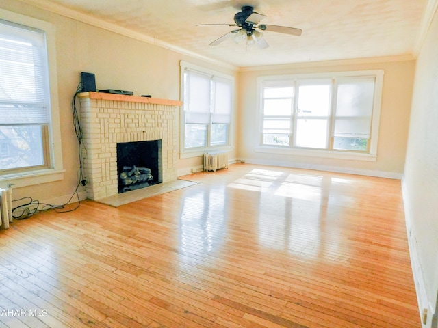 unfurnished living room featuring a fireplace, crown molding, radiator heating unit, and light wood-type flooring