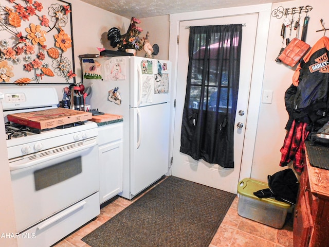 kitchen featuring white cabinetry, white appliances, a textured ceiling, and light tile patterned floors