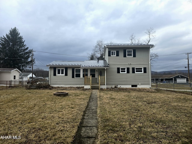 traditional-style house featuring a front yard, metal roof, and fence