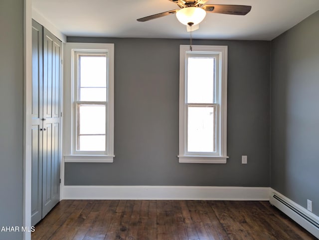 spare room featuring a baseboard heating unit, dark hardwood / wood-style floors, and ceiling fan