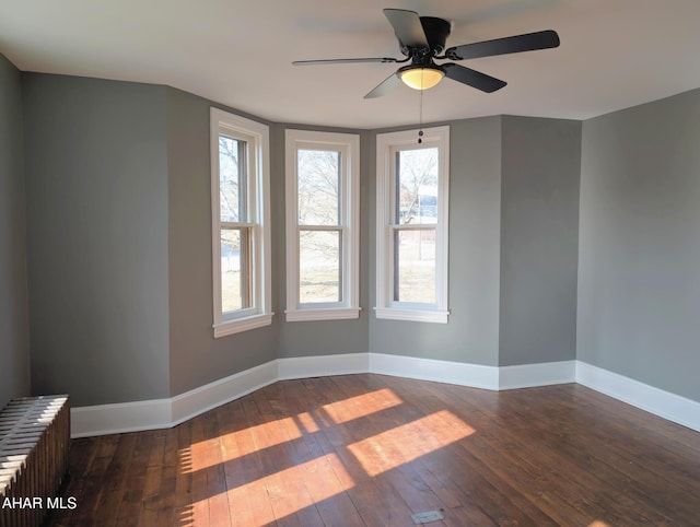 empty room featuring radiator heating unit, ceiling fan, and dark wood-type flooring