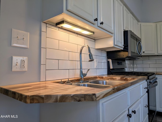 kitchen featuring stainless steel gas stove, butcher block countertops, white cabinetry, and tasteful backsplash