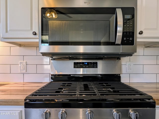 details featuring appliances with stainless steel finishes, wooden counters, white cabinets, and backsplash