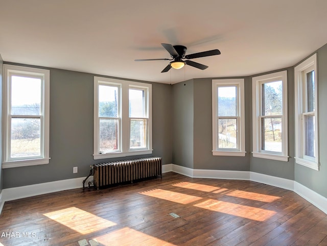 spare room featuring radiator, ceiling fan, and dark hardwood / wood-style flooring