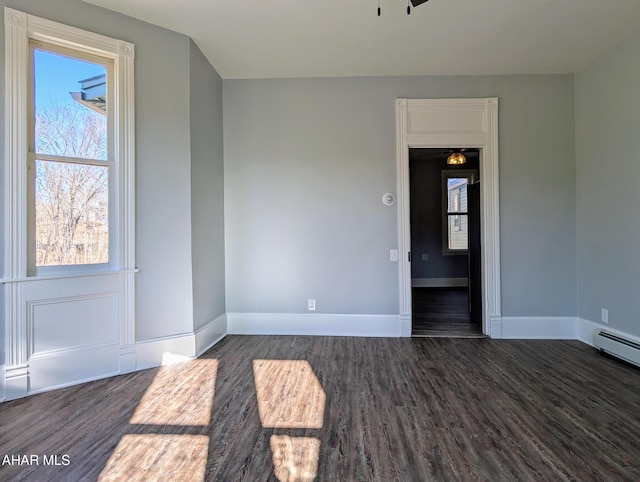 empty room with dark hardwood / wood-style flooring and baseboard heating