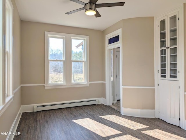 empty room with a baseboard heating unit, dark hardwood / wood-style floors, and ceiling fan