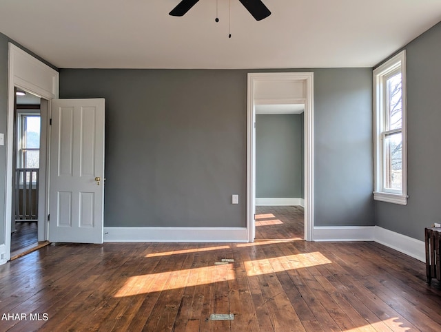 unfurnished bedroom featuring multiple windows, dark hardwood / wood-style floors, and ceiling fan