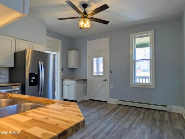 kitchen with white cabinetry, stainless steel fridge with ice dispenser, a healthy amount of sunlight, and baseboard heating