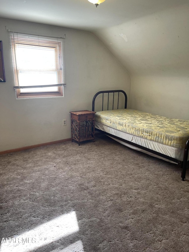 unfurnished bedroom with dark carpet and lofted ceiling