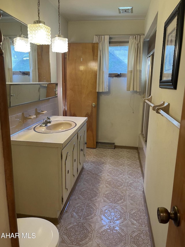 bathroom featuring decorative backsplash, vanity, a shower with shower door, and toilet