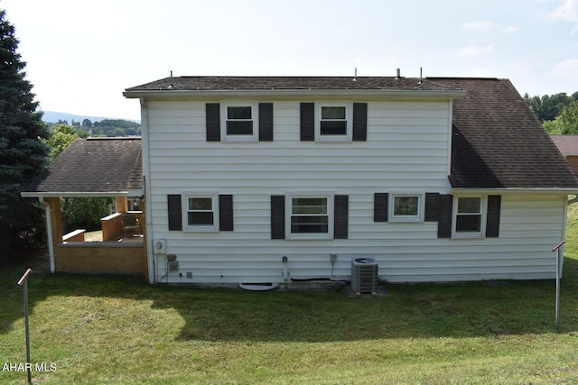 back of property with a lawn and central AC