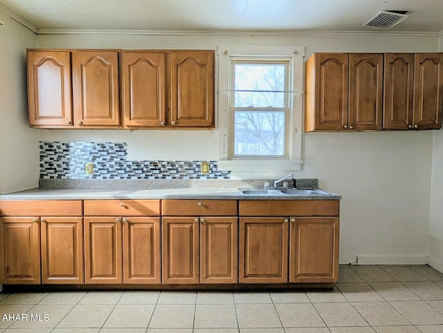 kitchen with tasteful backsplash, sink, crown molding, and light tile patterned flooring