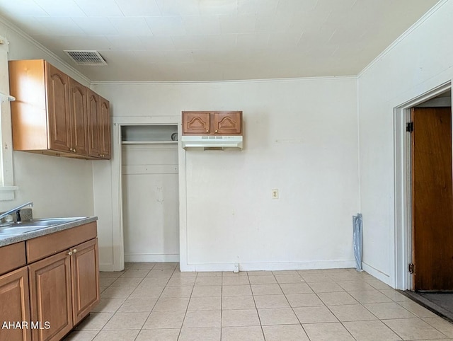 kitchen with light tile patterned floors, sink, and crown molding