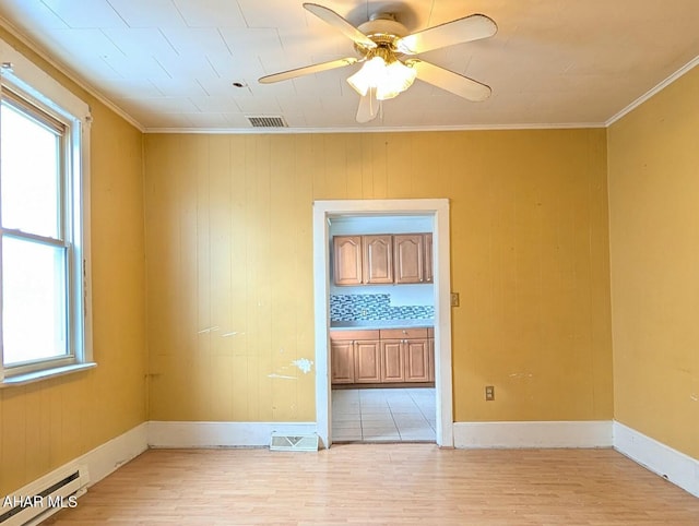 unfurnished room featuring light hardwood / wood-style floors, a baseboard heating unit, crown molding, and a healthy amount of sunlight