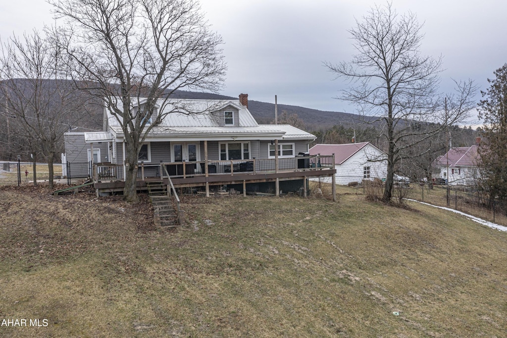 rear view of house featuring a wooden deck and a lawn