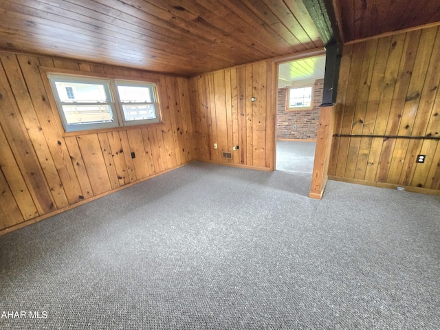 spare room featuring plenty of natural light, wood walls, wood ceiling, and carpet floors