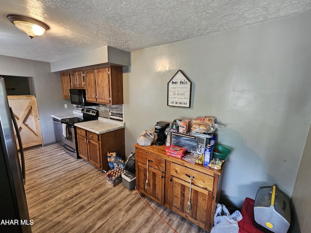 kitchen with decorative backsplash, appliances with stainless steel finishes, a textured ceiling, and light hardwood / wood-style flooring