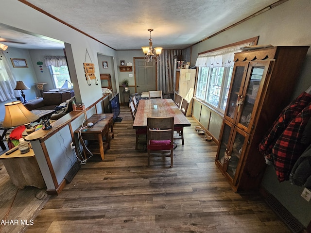 dining space featuring a textured ceiling, dark hardwood / wood-style flooring, an inviting chandelier, and plenty of natural light