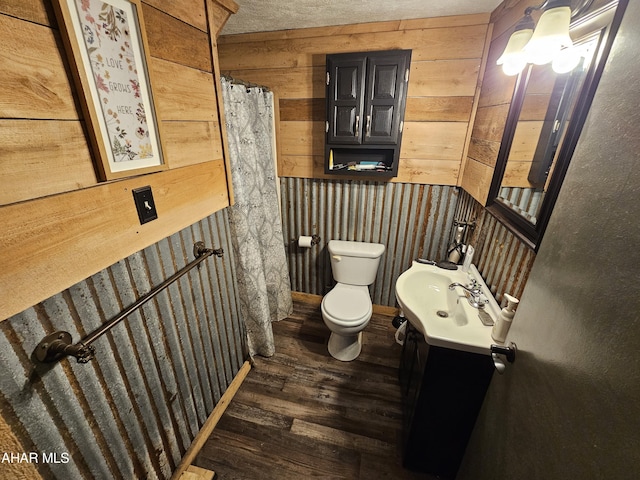 bathroom with wood walls, hardwood / wood-style floors, vanity, and toilet