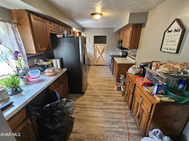 kitchen with light hardwood / wood-style flooring, stainless steel appliances, and a textured ceiling