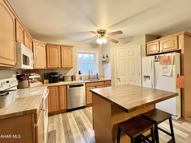 kitchen with butcher block countertops, white appliances, light brown cabinets, and a sink