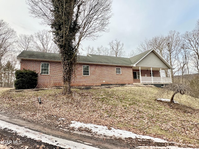 ranch-style home featuring covered porch and brick siding