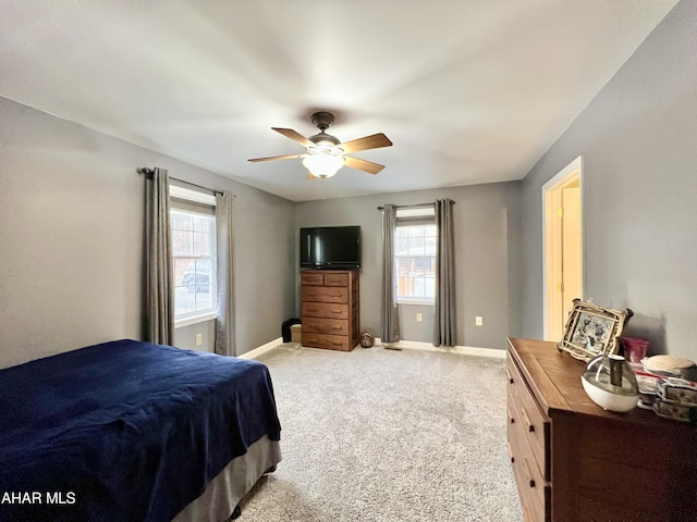 bedroom featuring light colored carpet, ceiling fan, baseboards, and multiple windows