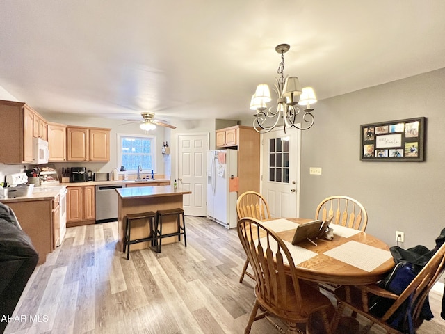 dining area with light wood-style flooring and ceiling fan with notable chandelier