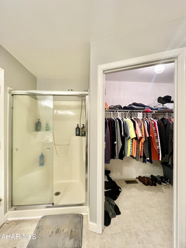 bathroom with a walk in closet and a shower stall