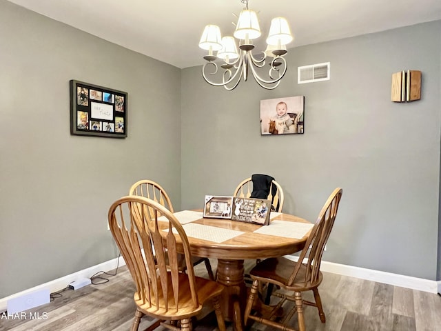 dining space with a chandelier, visible vents, baseboards, and wood finished floors