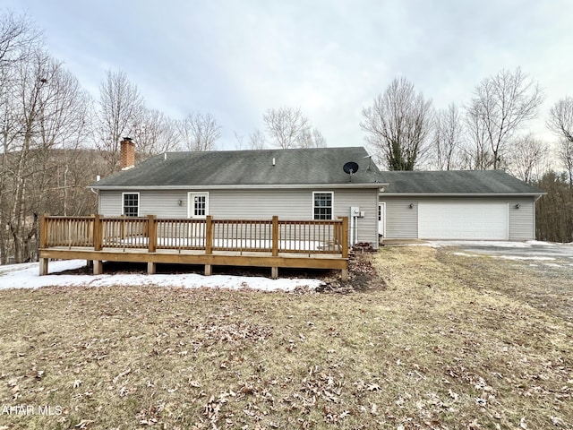 back of house with an attached garage, a chimney, and a deck