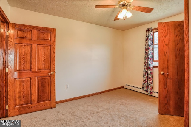 spare room featuring a baseboard heating unit, a textured ceiling, light colored carpet, and ceiling fan