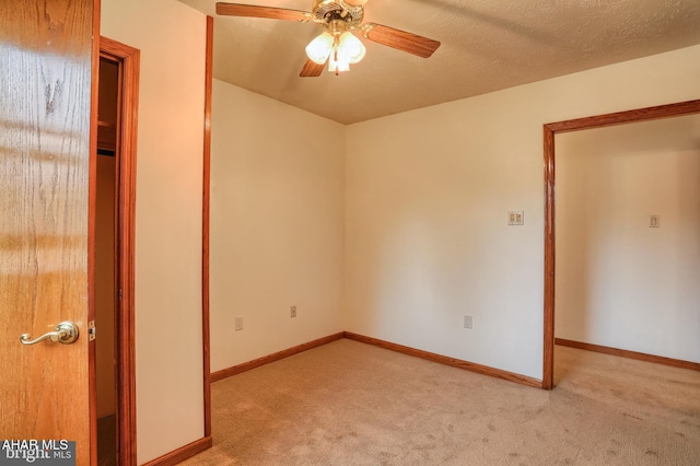 interior space with a textured ceiling, light colored carpet, and ceiling fan