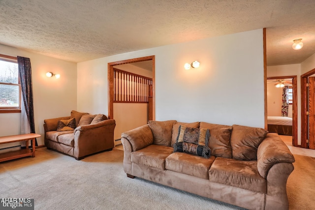 living room with baseboard heating, a textured ceiling, and light colored carpet