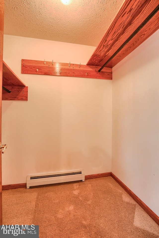 spacious closet with carpet floors and a baseboard radiator