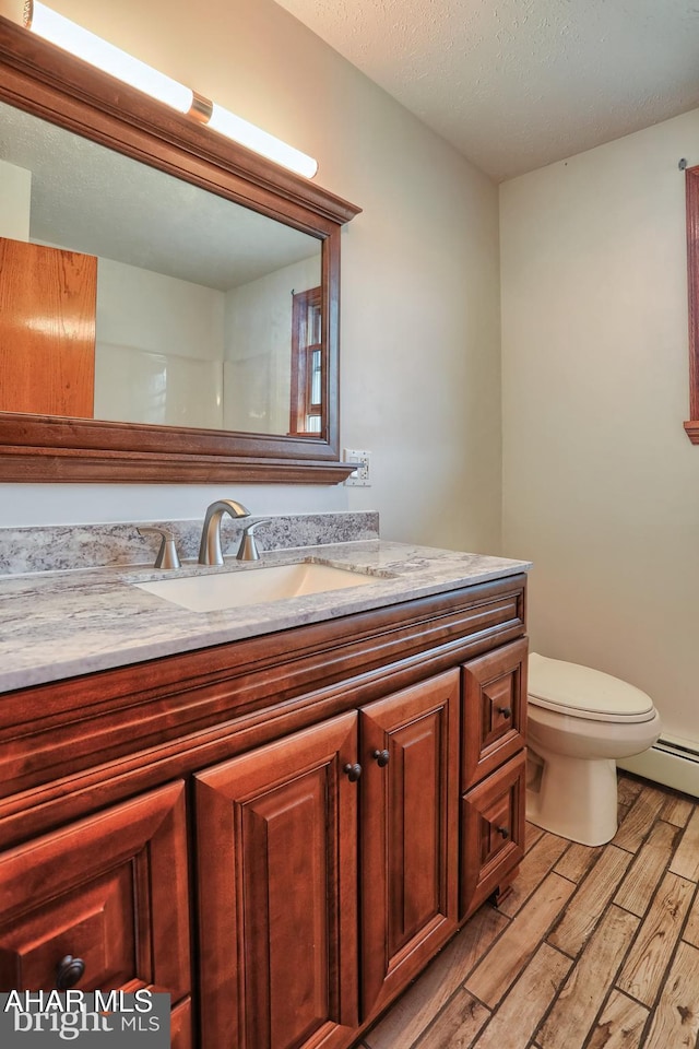 bathroom featuring toilet, hardwood / wood-style flooring, a textured ceiling, and vanity