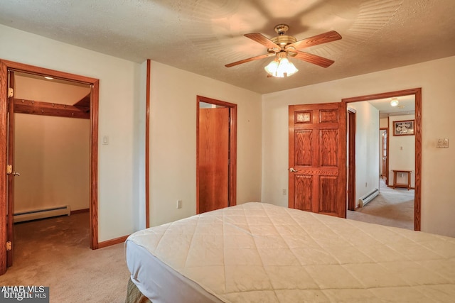 bedroom with a baseboard heating unit, a closet, light colored carpet, and a walk in closet