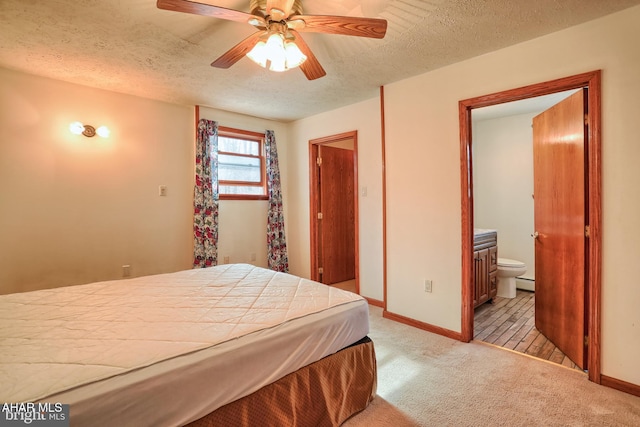 bedroom with a baseboard radiator, a textured ceiling, ceiling fan, ensuite bathroom, and light colored carpet