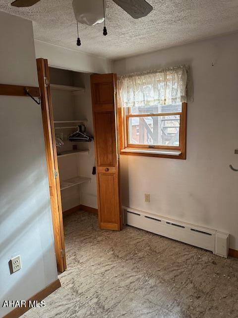 unfurnished bedroom featuring ceiling fan, a closet, a baseboard radiator, and a textured ceiling