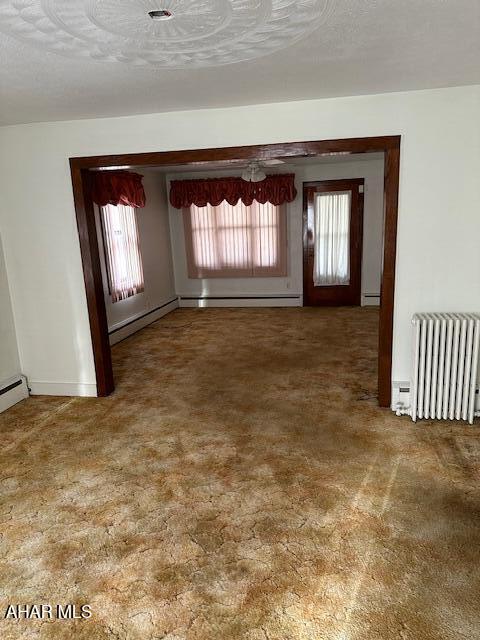 spare room with carpet flooring, radiator heating unit, a textured ceiling, and a baseboard radiator