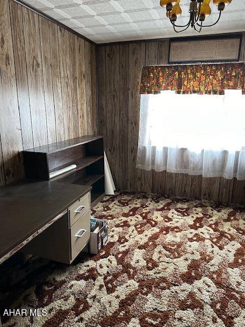 miscellaneous room featuring carpet flooring, wood walls, and a notable chandelier