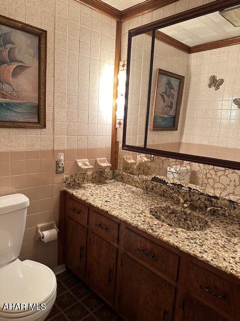 bathroom featuring vanity, tile patterned flooring, toilet, ornamental molding, and tile walls