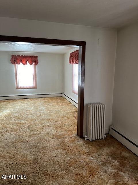 carpeted empty room featuring radiator heating unit and a baseboard radiator