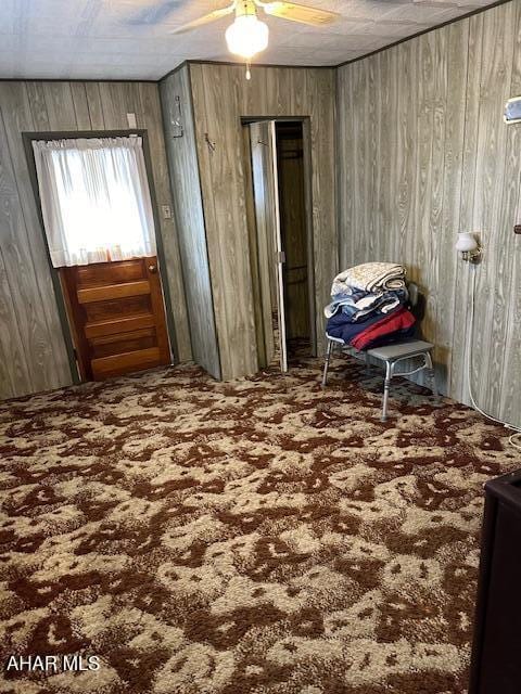 miscellaneous room featuring ceiling fan and wood walls