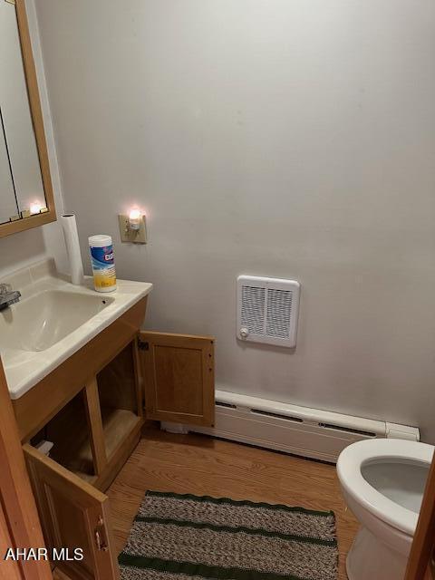 bathroom featuring a baseboard radiator, toilet, hardwood / wood-style flooring, and sink