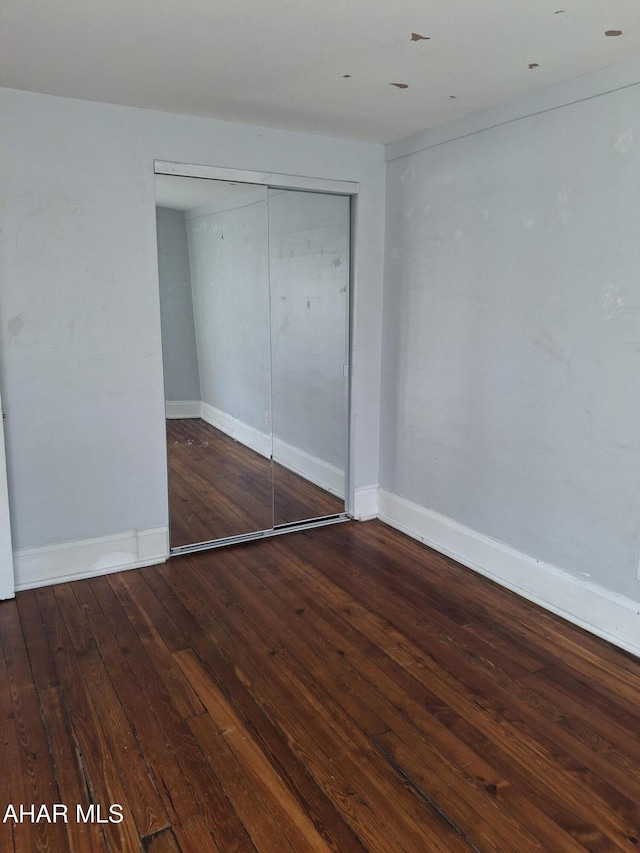 unfurnished bedroom with wood-type flooring and a closet