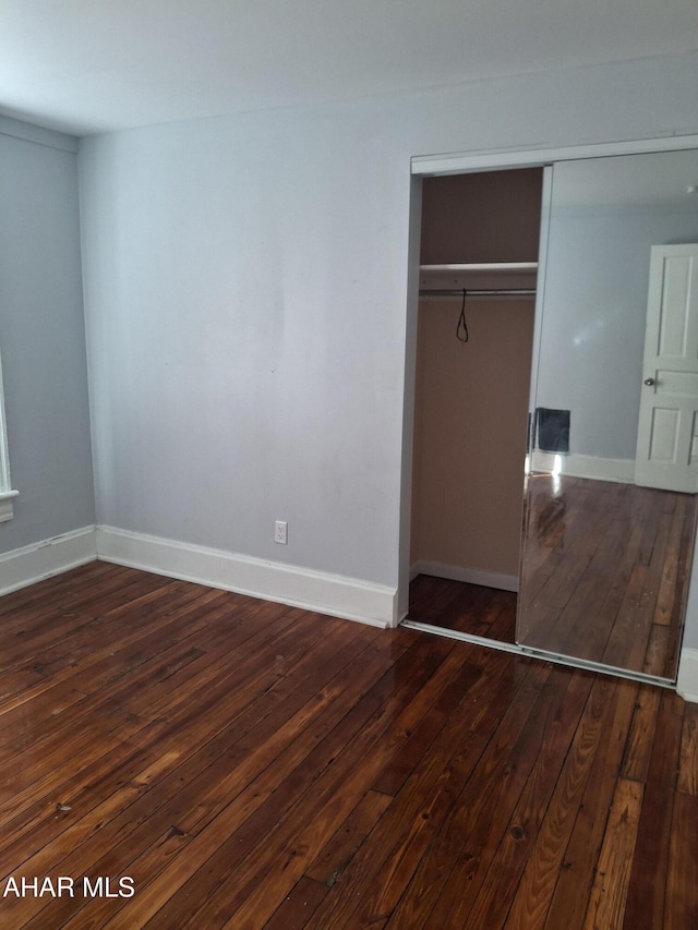 unfurnished bedroom featuring dark hardwood / wood-style flooring and a closet